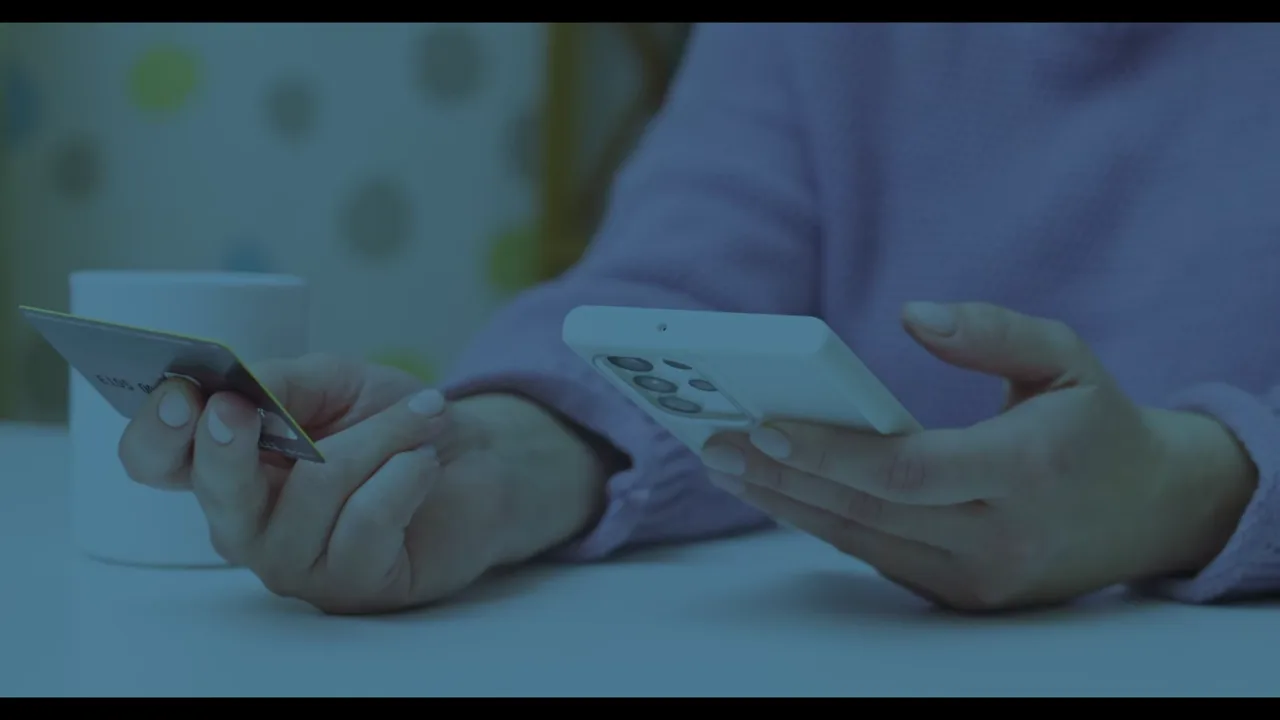 Persona pagando desde su teléfono con la tarjeta en la mano